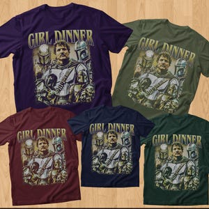 May include: Five short-sleeved t-shirts in various colors: purple, olive green, burgundy, navy blue, and dark green. Each shirt features a graphic of a man with helmeted figures and the text "GIRL DINNER" in a gold font.