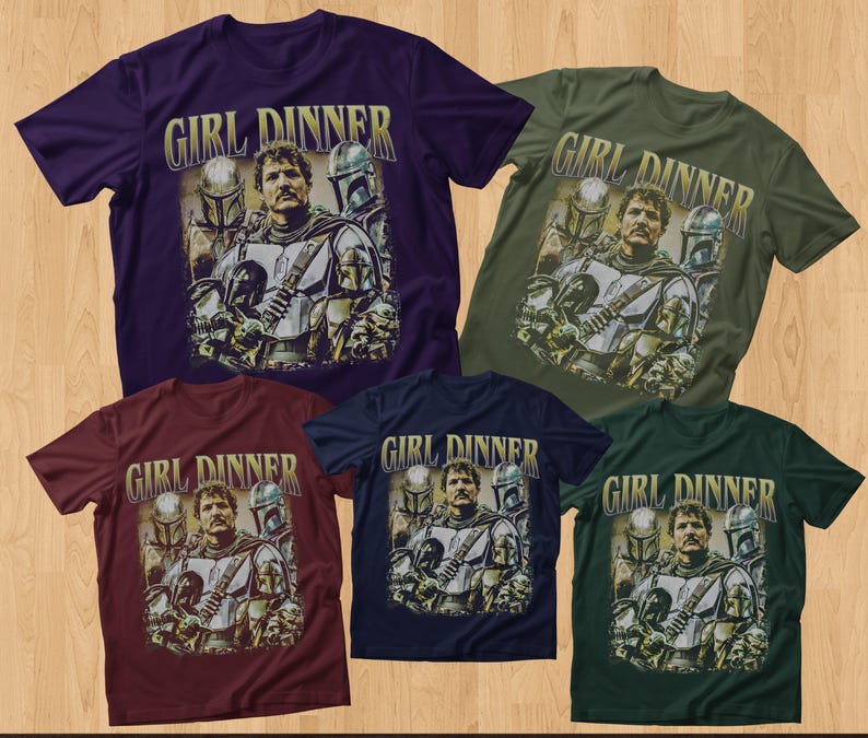 May include: Five short-sleeved t-shirts in various colors: purple, olive green, burgundy, navy blue, and dark green. Each shirt features a graphic of a man with helmeted figures and the text "GIRL DINNER" in a gold font.