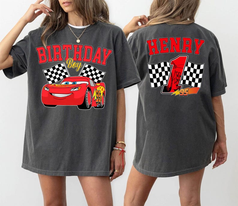 Pu&ograve; includere: T-shirt grigio scuro con un'auto da corsa rossa dei cartoni animati e la scritta "BIRTHDAY BOY". La parte posteriore della maglietta ha il nome "HENRY", il numero 1 e bandiere a scacchi. Il design &egrave; rosso e giallo.