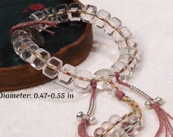 May include: Clear quartz crystal bracelet with cube-shaped beads, measuring 0.47-0.55 inches in diameter. The bracelet features pink and multicolored cords, metal accents, and a decorative charm. The beads are strung on a clear cord.
