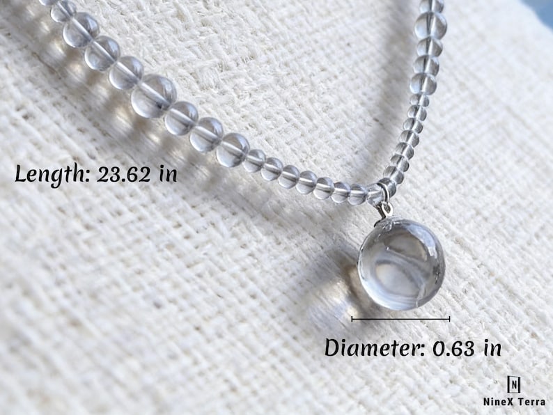 May include: A clear quartz necklace with a round pendant. The necklace is 23.62 inches long, and the pendant has a diameter of 0.63 inches. The necklace is made of small, clear beads.