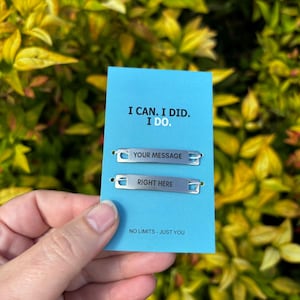 Puede incluir: Una tarjeta azul con el texto "I CAN. I DID. I DO." y las frases "YOUR MESSAGE" y "RIGHT HERE" en etiquetas de metal plateado. La tarjeta también tiene el texto "NO LIMITS - JUST YOU".