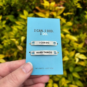 May include: A blue card with the text "I CAN. I DID. I DO." and the phrase "NO LIMITS - JUST YOU." Two silver metal bars read "I CAN DO" and "HARD THINGS."