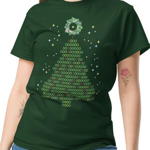 May include: Dark green t-shirt featuring a binary code Christmas tree design. The tree is composed of green numbers and symbols, with a decorative element at the top. The shirt is a comfortable, casual style.