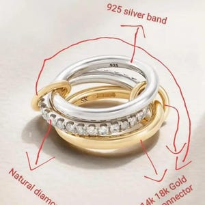 May include: A set of three interlocking rings. One ring is silver with the marking "925", another is gold, and the third is gold with a row of diamonds. The rings are connected by gold connectors.