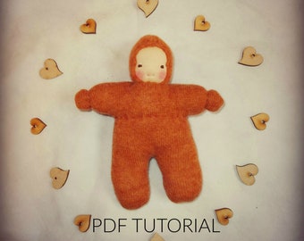 May include: A tutorial for making a handmade doll, called a Chublet, with a PDF tutorial. The doll is made of orange fabric and has a hood. The doll is surrounded by wooden hearts.