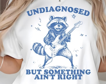 Undiagnosed But Something Ain’t Right PNG SVG, Funny Rockstar Raccoon Guitar Design, Neurodivergent Mental Health Humor Png
