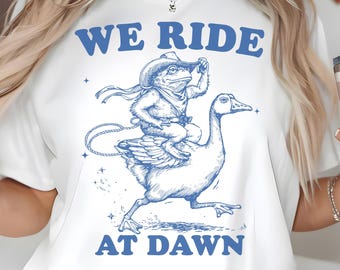 We Ride at Dawn PNG SVG, Cowboy Raccoon Riding Goose, Funny Western Chaos Meme Quote, Whimsical Gamer Gift