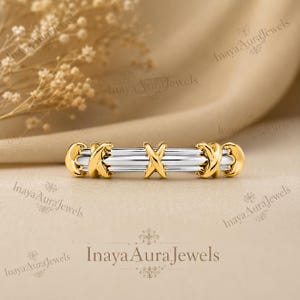 May include: A two-tone ring featuring a central silver-colored band with three gold-colored X-shaped accents positioned at the center and on both ends. The design consists of smooth, polished metal surfaces with a reflective finish throughout the piece.