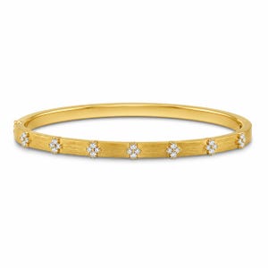 Puede incluir: Un brazalete rígido articulado de oro amarillo con un acabado mate cepillado. La superficie exterior presenta un patrón repetitivo de pequeños motivos florales de cuatro pétalos, cada uno engastado con cuatro diminutas piedras claras.