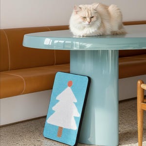 May include: A rectangular mat featuring a white Christmas tree graphic with a brown trunk and orange star on a light blue textured background. The text o!cute is displayed at the top and bottom, with the phrase For the love that paws give for the o!cute moments we live.