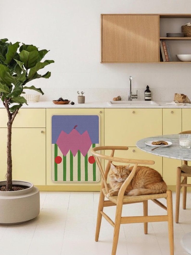 May include: A kitchen scene with a yellow cabinet and a colorful mat with a geometric design. A ginger cat rests on a wooden chair. A potted plant and a round table are also visible.