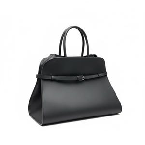 May include: A black handbag with a trapezoid shape and two top handles. The bag features a thin belt with a silver buckle around the middle. The bag is made of a smooth material and has a minimalist design.