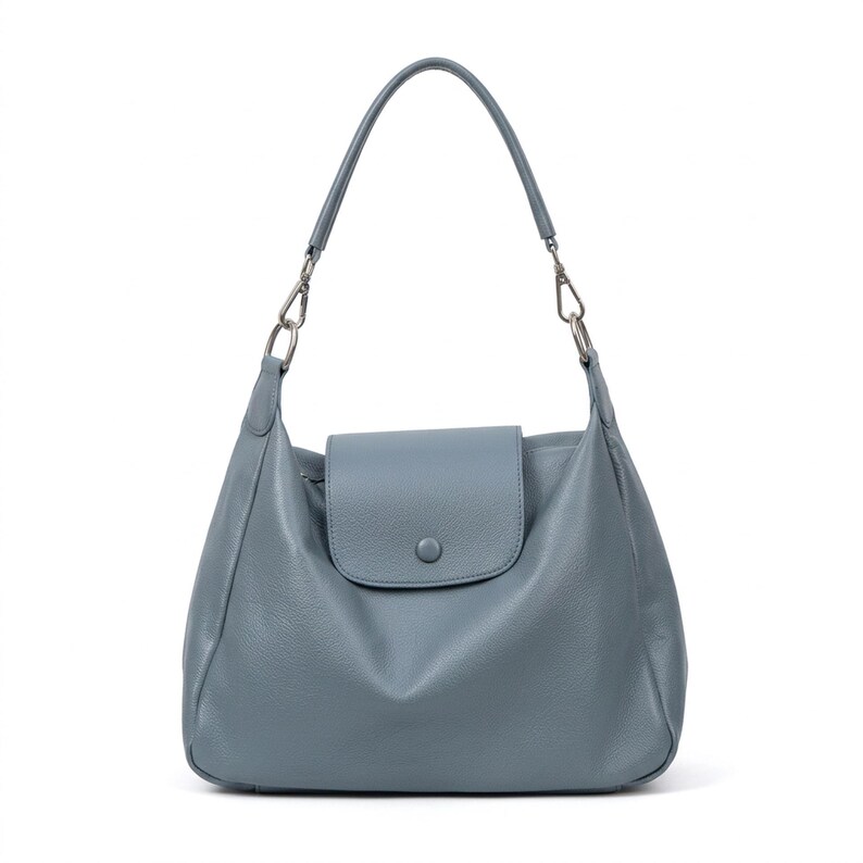 May include: A blue-grey leather shoulder bag with a flap closure and a single handle. The bag has silver-toned hardware and a rounded shape. The bag is approximately 35 cm wide and 30 cm tall.