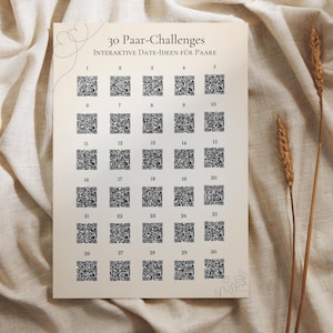 Könnte beinhalten: Ein beiger Druck mit dem Text "30 Paar-Challenges INTERAKTIVE DATE-IDEEN FÜR PAARE" und 30 QR-Codes. Der Druck befindet sich auf einem beigen Stoff mit zwei Weizenähren.