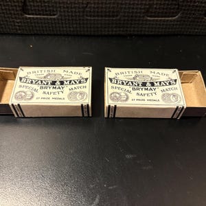 May include: Two vintage matchboxes, each with a tan and brown color scheme. The boxes are labeled "BRYANT & MAY'S BRYMAY MATCH" with "SPECIAL SAFETY" text. The boxes are open, revealing the interior. The text "27 PRIZE MEDALS" is also visible.