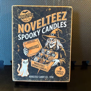May include: A rectangular box of Novelteez Spooky Candles featuring a black background with a witch illustration, a white cat, and a box containing nine small candles. The text reads Novelteez Spooky Candles, Novelteez Candy Co., 1958, and 9 Candles Per Box.