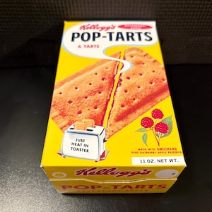 May include: A yellow rectangular box of Kellogg's Pop-Tarts containing 6 tarts. The front features a graphic of two toasted pastries, a toaster with the text JUST HEAT IN TOASTER, and raspberries. The box is labeled 11 OZ. NET WT.