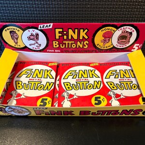 May include: A vintage display box of "Fink Buttons" metal novelty buttons. The box is red and yellow, with the text "Fink Buttons" and illustrations. Each button pack is 5 cents.