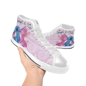 Puede incluir: Zapatillas altas de lona con un dise&ntilde;o rosa y blanco con los personajes Angel y Stitch. Las zapatillas tienen cordones blancos, una puntera blanca y una suela negra. Las palabras "Angel & Stitch" est&aacute;n impresas en el lateral.