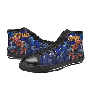 Op de afbeelding: Hoge canvas sneakers met een Spiderman-ontwerp. De schoenen hebben een zwarte neus, zwarte veters en een zwarte zool. De zijkanten van de schoenen tonen Spiderman in actie tegen een stadsgezicht achtergrond, met het woord "Spiderman" in goud.