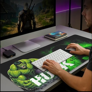 Könnte beinhalten: Eine schwarze und grüne erweiterte Mausunterlage im Hulk-Design. Das Pad zeigt eine große Grafik von Hulk mit dem Wort "HULK" in Weiß. Eine weiße Tastatur und Maus befinden sich auf dem Pad, mit einem Computermonitor im Hintergrund.