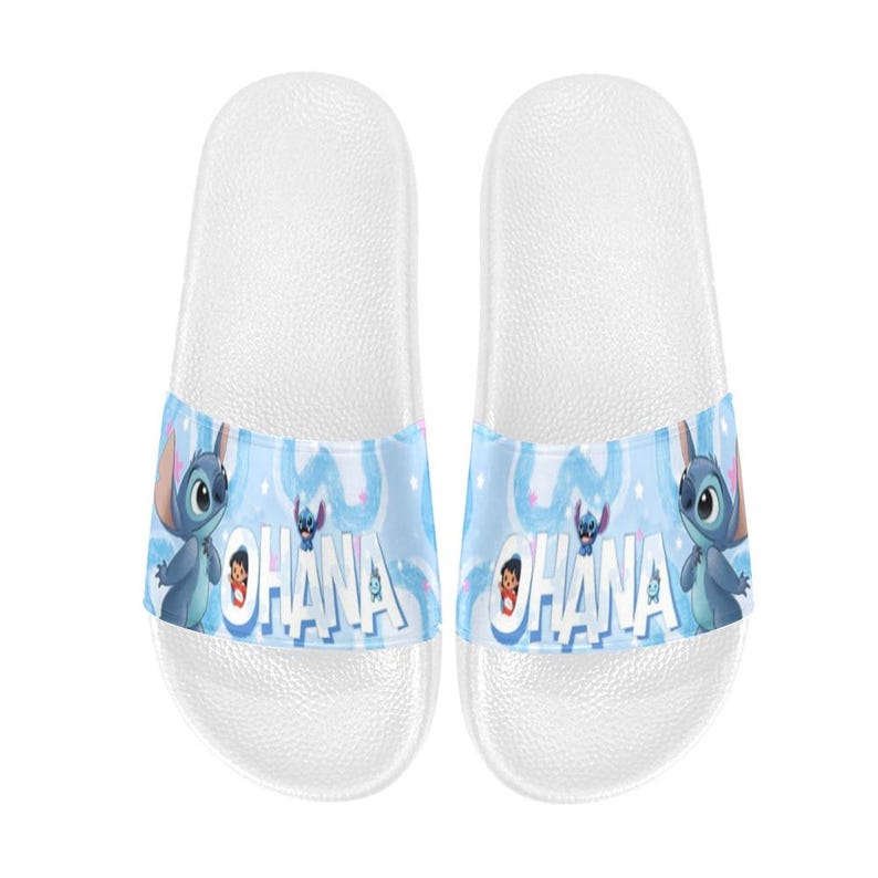 Puede incluir: Sandalias deslizantes blancas con una banda azul que presenta a Stitch de Lilo & Stitch. La banda muestra la palabra "Ohana" e im&aacute;genes de dibujos animados de Stitch. Estas sandalias est&aacute;n dise&ntilde;adas para uso casual.