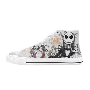 Puede incluir: Zapatillas altas blancas con un dise&ntilde;o gr&aacute;fico colorido de "Pesadilla antes de Navidad". El dise&ntilde;o incluye personajes como Jack Skellington, Sally y otros. Las zapatillas tienen cordones blancos y una suela de goma blanca.