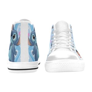 Puede incluir: Zapatillas altas blancas con un dise&ntilde;o de personaje de dibujos animados azul. Las zapatillas tienen una suela y cordones de goma blancos. El personaje est&aacute; representado en los laterales y en la parte trasera de los zapatos, sobre un fondo azul y blanco.