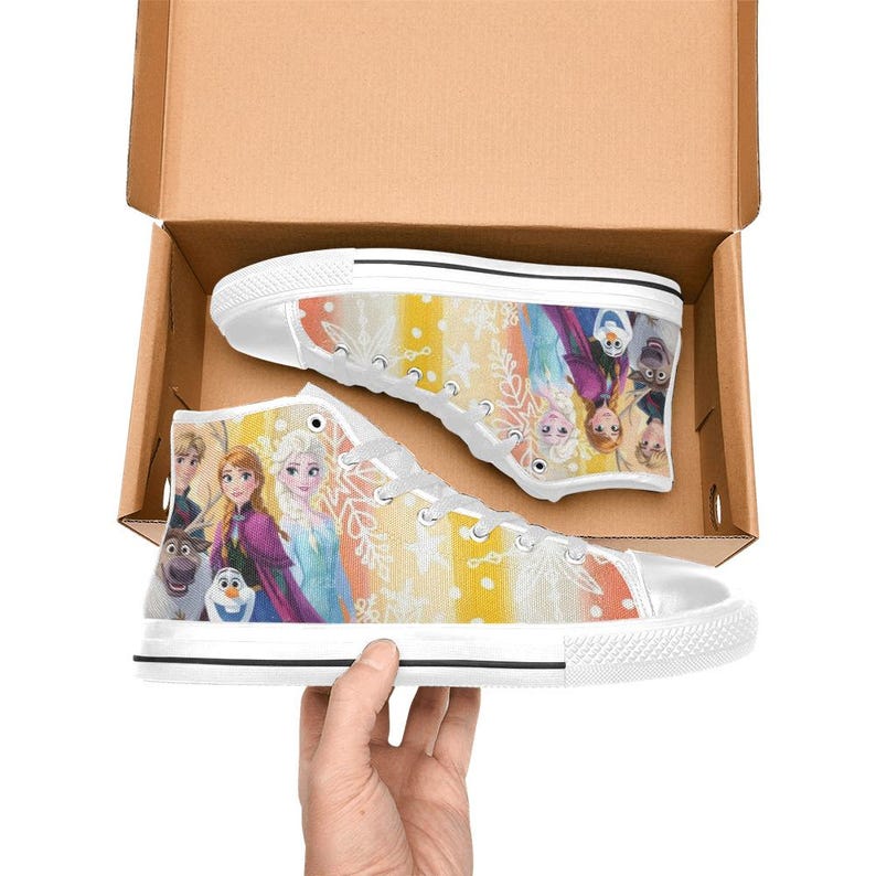 May include: White high-top sneakers featuring a colorful design with characters from the animated movie. The shoes have a white rubber sole and laces. The design includes images of Elsa, Anna, Olaf, and other characters.