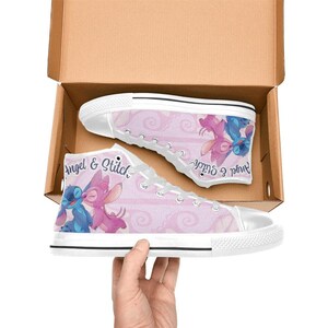 Puede incluir: Zapatillas altas de lona con un fondo rosa y un patr&oacute;n de remolino repetido. Las zapatillas muestran el texto "Angel & Stitch" y un gr&aacute;fico de los personajes. Los zapatos est&aacute;n en una caja de cart&oacute;n.