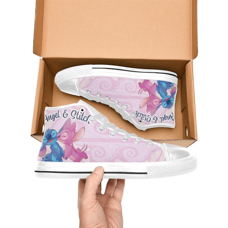 Puede incluir: Zapatillas altas de lona con un fondo rosa y un patr&oacute;n de remolino repetido. Las zapatillas muestran el texto "Angel & Stitch" y un gr&aacute;fico de los personajes. Los zapatos est&aacute;n en una caja de cart&oacute;n.