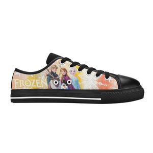 Puede incluir: Zapatillas bajas de lona con personajes de la pel&iacute;cula de Disney "Frozen". Los zapatos tienen suela y puntera de goma negra, con cordones negros. La palabra "FROZEN" est&aacute; impresa en amarillo en el lateral.