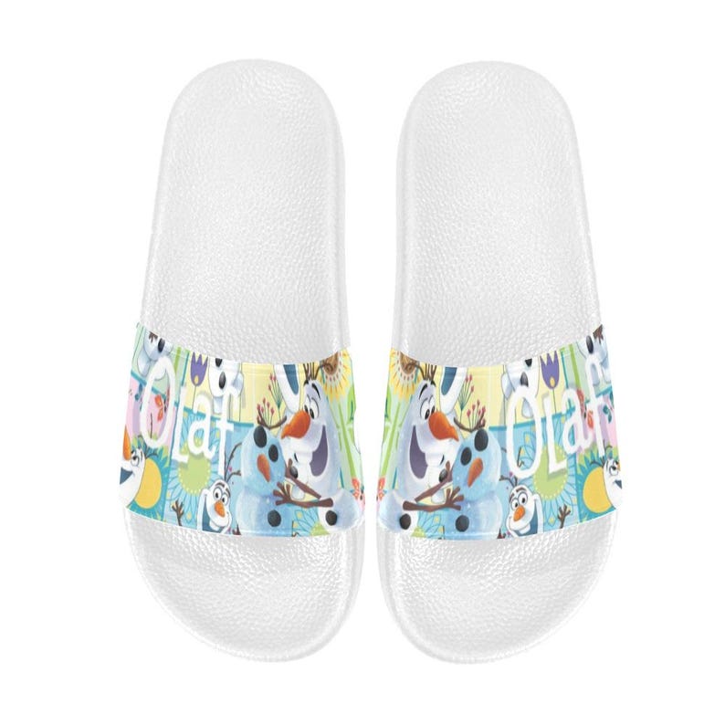 Puede incluir: Un par de sandalias deslizantes blancas con una banda colorida con el personaje Olaf de Frozen. La banda tiene un fondo azul, amarillo y verde con la palabra "Olaf" e im&aacute;genes de Olaf.