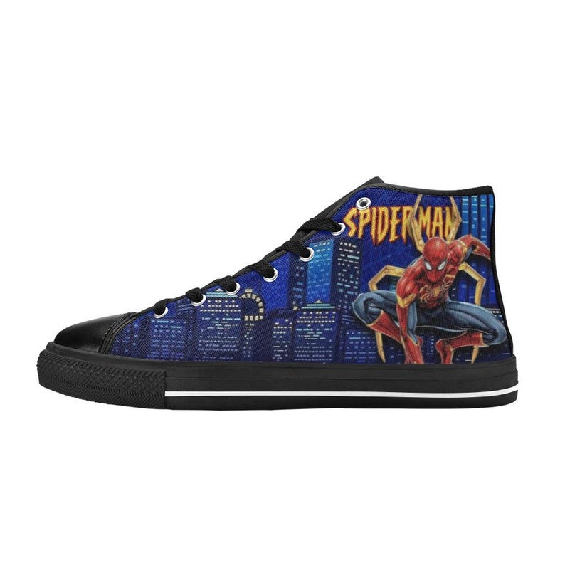 Op de afbeelding: Hoge canvas sneaker met een Spiderman-afbeelding. De schoen heeft een zwarte neus en zool, met een blauwe skyline-achtergrond. Het Spiderman-logo is zichtbaar aan de zijkant.