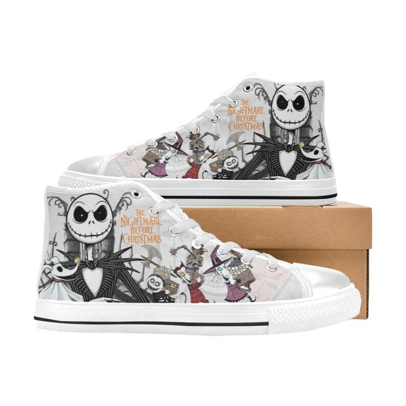 Puede incluir: Zapatillas altas blancas con personajes de "Pesadilla antes de Navidad". Los zapatos muestran a Jack Skellington, Sally y otros personajes en un dise&ntilde;o en blanco y negro. El texto "The Nightmare Before Christmas" tambi&eacute;n es visible.