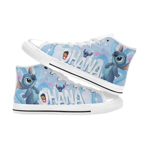 Puede incluir: Un par de zapatillas altas de lona con un fondo azul claro con un patr&oacute;n repetido de Stitch y otros personajes. La palabra "OHANA" est&aacute; impresa en blanco. Cordones y suelas blancos completan el dise&ntilde;o.