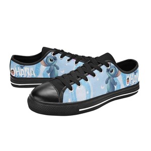 May include: Pair of low-top canvas sneakers featuring a light blue background with a cartoon character and the word "OHANA". The shoes have black laces, toe caps, and soles with a white stripe.