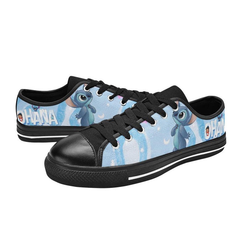 May include: Pair of low-top canvas sneakers featuring a light blue background with a cartoon character and the word "OHANA". The shoes have black laces, toe caps, and soles with a white stripe.