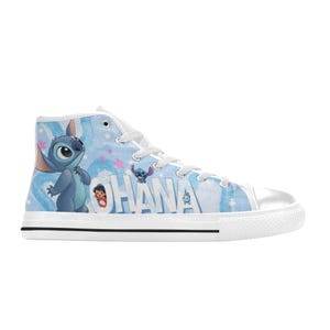 Puede incluir: Zapatilla alta de lona con un dise&ntilde;o azul y blanco con la palabra "OHANA" y personajes de dibujos animados. La zapatilla tiene puntera, cordones y suela blancos con una franja negra.