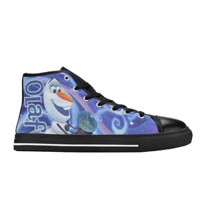 Puede incluir: Zapatilla alta de lona con una imagen de dibujos animados de Olaf de Frozen. La zapatilla tiene puntera, cordones y ribete de suela negros. El fondo es un dise&ntilde;o de remolino azul y morado con el nombre "Olaf" impreso verticalmente.