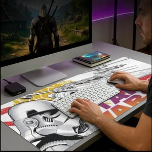 May include: A rectangular Star Wars-themed desk mat featuring a Stormtrooper helmet and X-wing fighter illustrations. The mat has a white background with yellow and red accents, and the words "STAR WARS" are visible.