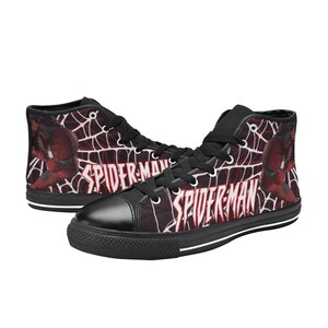 May include: High-top canvas sneakers featuring a Spider-Man design. The shoes have a black toe cap, laces, and sole. The sides display a red and black web pattern with the words "Spider-Man".