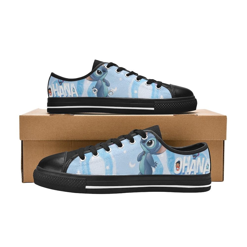 May include: Pair of blue low-top sneakers featuring a cartoon character design. The shoes have black soles and laces, with the word "OHANA" printed on the side. The background of the shoes is light blue with white clouds.
