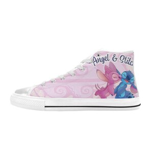 Puede incluir: Zapatilla alta de lona rosa con un dise&ntilde;o de Angel y Stitch bes&aacute;ndose. El zapato tiene cordones blancos, una suela blanca y las palabras "Angel & Stitch" en cursiva. El fondo tiene un patr&oacute;n de remolino.