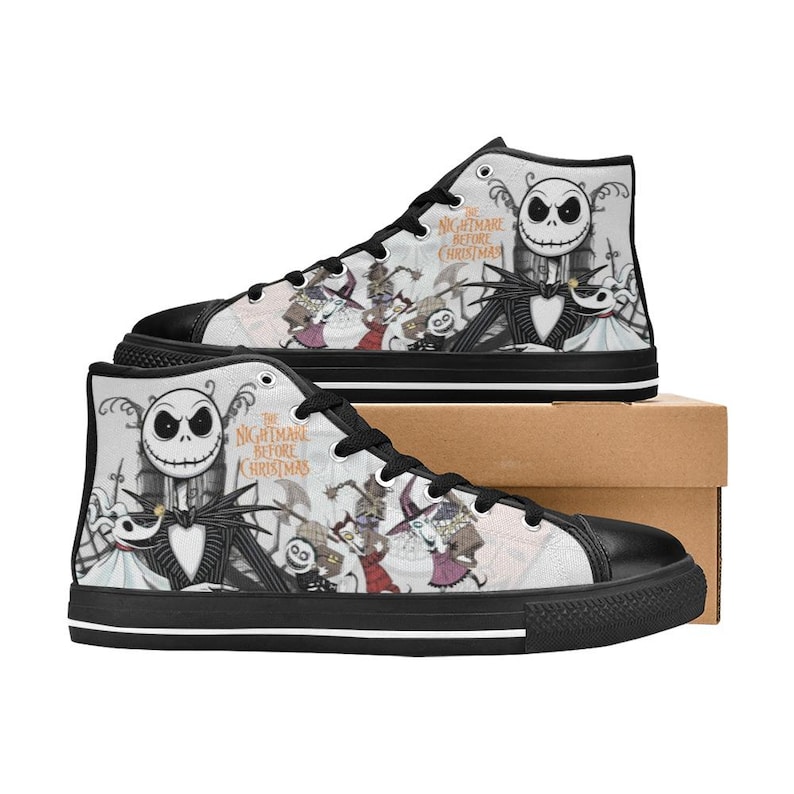 Puede incluir: Zapatillas altas de lona con un dise&ntilde;o en blanco y negro con personajes de "Pesadilla antes de Navidad". Los zapatos tienen cordones negros, puntera negra y suela negra. El texto "The Nightmare Before Christmas" es visible.