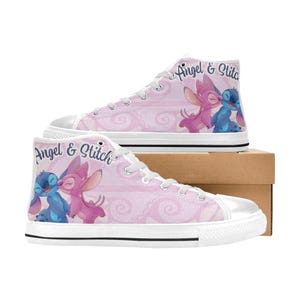 Puede incluir: Zapatillas altas de lona con un fondo rosa estampado y las palabras "Angel & Stitch". Las zapatillas presentan un dise&ntilde;o de personajes de dibujos animados azules y rosas. Tienen suelas y cordones blancos.