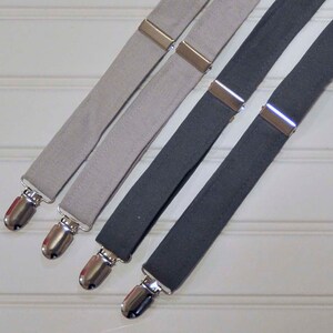 May include: Three pairs of suspenders, one pair is gray, one pair is light gray, and one pair is dark gray. The suspenders have silver metal clips.