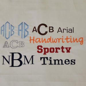 May include: A white fabric swatch with different embroidery styles of the letters "ACB" and "NBM". The styles include a monogram, block letters, handwriting, sporty, Arial, and Times New Roman fonts.