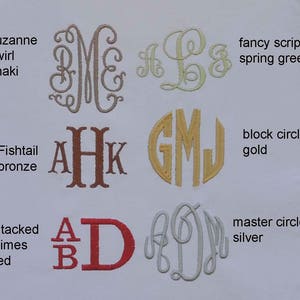 May include: A variety of monogram styles and fonts are shown in different colors, including khaki, bronze, gold, silver, and red. The monograms are embroidered on a white fabric background. The text "suzanne swirl khaki", "fishtail bronze", "block circle gold", "master circle silver", "stacked times red", and "fancy script spring green" are also shown.